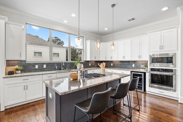 kitchen featuring appliances with stainless steel finishes, wine cooler, white cabinets, and a center island