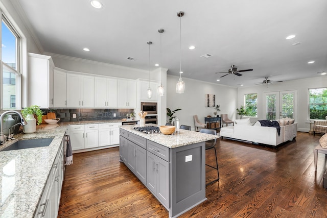 kitchen featuring a kitchen island, white cabinetry, dark hardwood / wood-style floors, decorative light fixtures, and sink