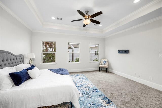 bedroom featuring ceiling fan, crown molding, a tray ceiling, and carpet flooring