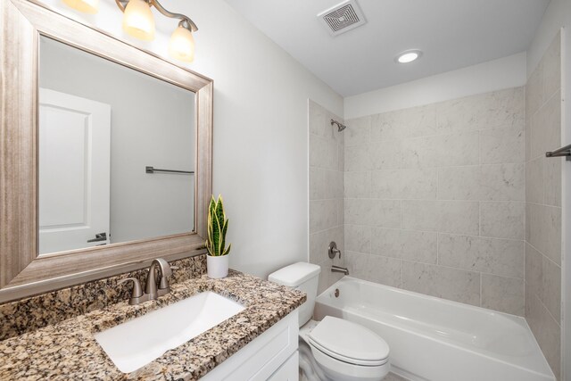 full bathroom featuring tiled shower / bath combo, vanity, and toilet