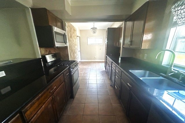 kitchen featuring stainless steel appliances, dark tile patterned floors, dark brown cabinetry, and sink