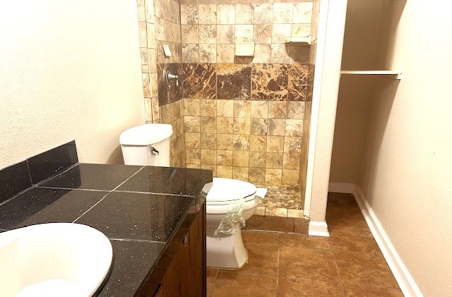 bathroom with tiled shower, vanity, and toilet