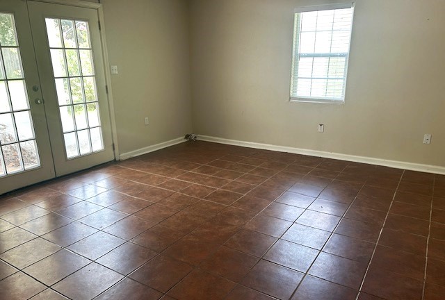 unfurnished room featuring dark tile patterned floors and french doors