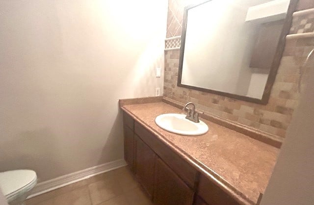 bathroom featuring vanity, toilet, tile patterned floors, and decorative backsplash