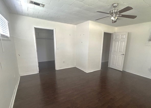 empty room featuring dark wood-type flooring and ceiling fan