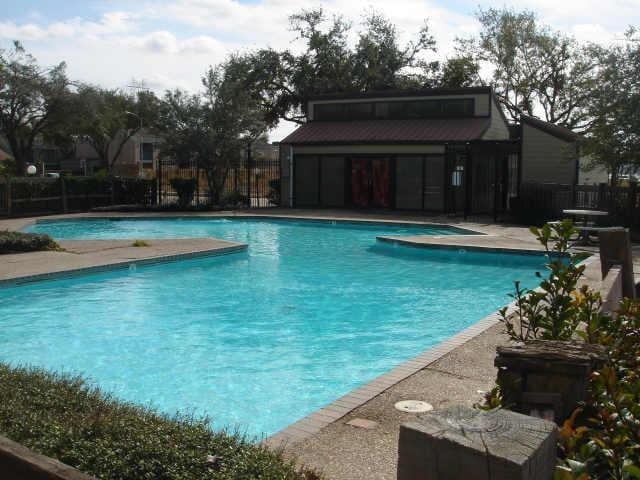 pool featuring a patio area, fence, and an outdoor structure