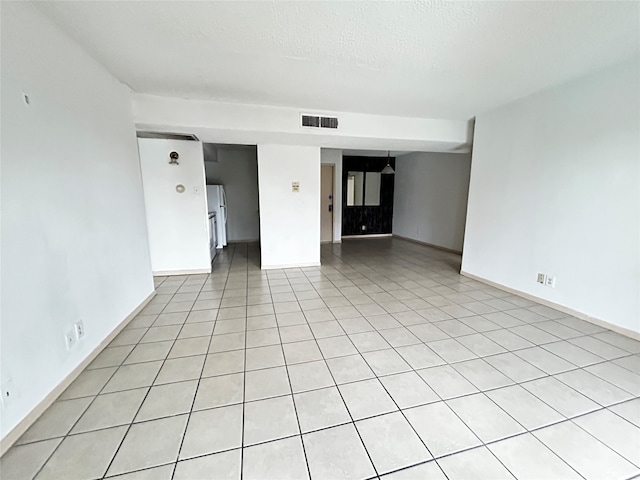 empty room featuring light tile patterned flooring and a textured ceiling