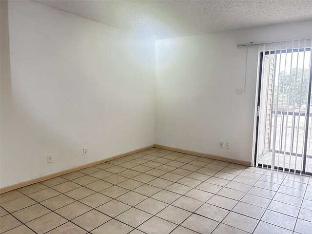 tiled spare room featuring a textured ceiling