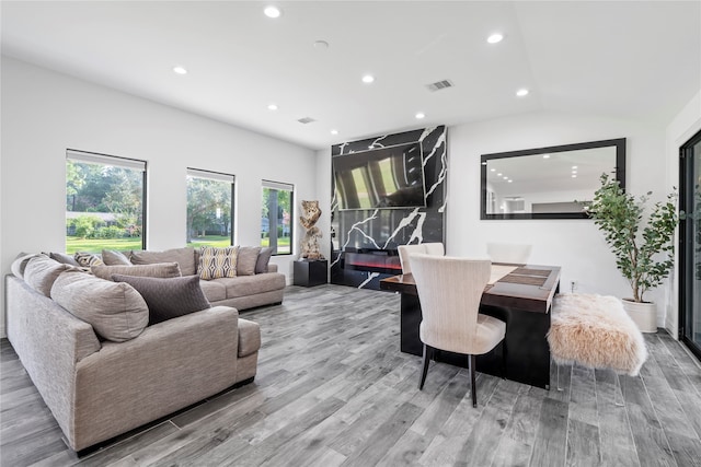 living room with vaulted ceiling, a wealth of natural light, and light hardwood / wood-style flooring