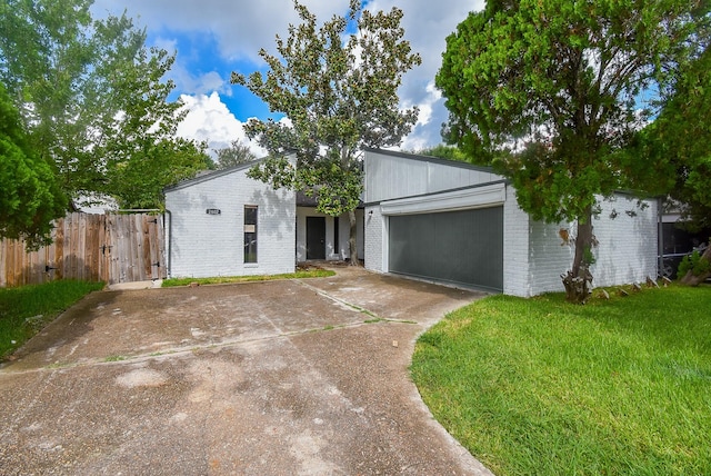 mid-century home with a garage, brick siding, fence, driveway, and a front yard