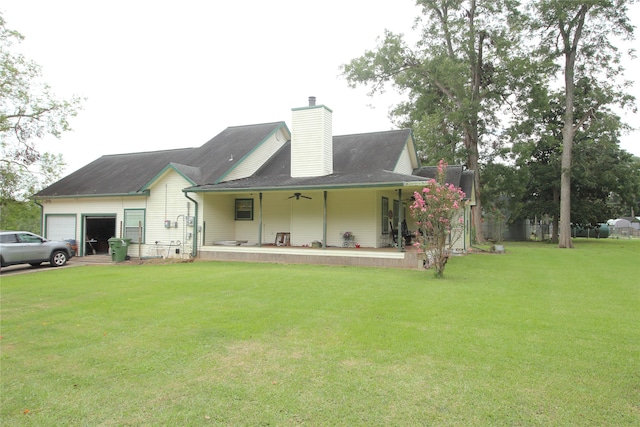 back of house with a garage, ceiling fan, covered porch, and a yard