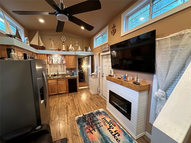 kitchen featuring light wood-type flooring, high vaulted ceiling, stainless steel fridge, sink, and ceiling fan