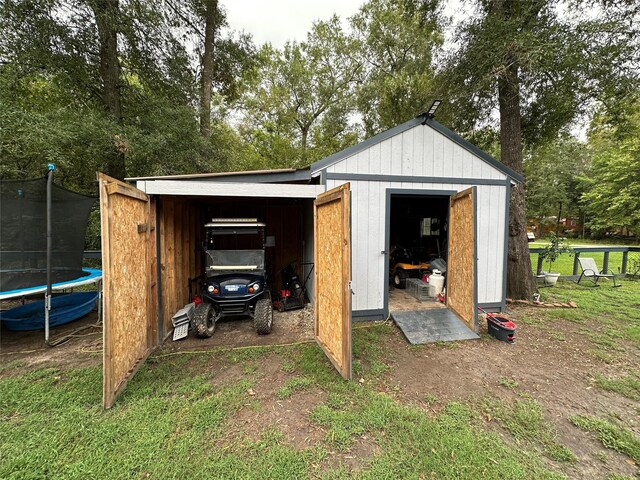 view of outbuilding with a trampoline and a yard