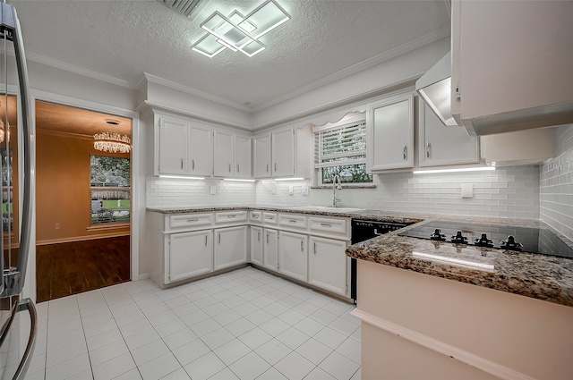 kitchen featuring light wood-type flooring, dark stone counters, crown molding, white cabinetry, and sink