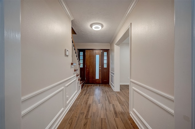 entryway with a textured ceiling, crown molding, and light hardwood / wood-style floors