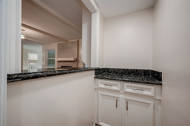 kitchen with washer / clothes dryer, white cabinets, dark stone countertops, and a textured ceiling