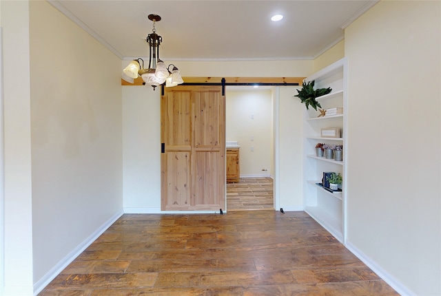 unfurnished dining area with wood-type flooring, crown molding, and a barn door