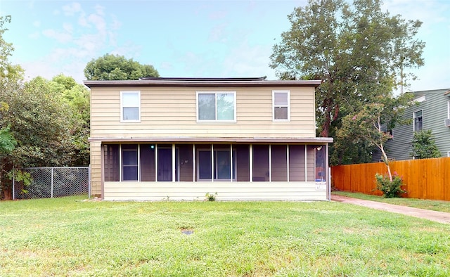 rear view of house featuring a sunroom and a yard