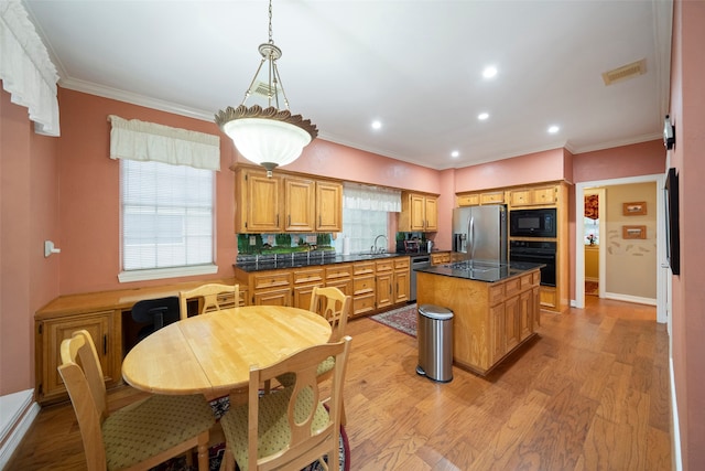 kitchen featuring sink, tasteful backsplash, a kitchen island, black appliances, and light hardwood / wood-style floors