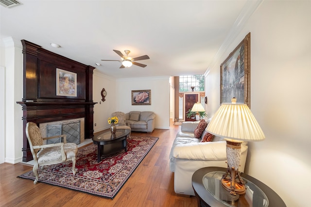 living room featuring ornamental molding, wood-type flooring, and ceiling fan