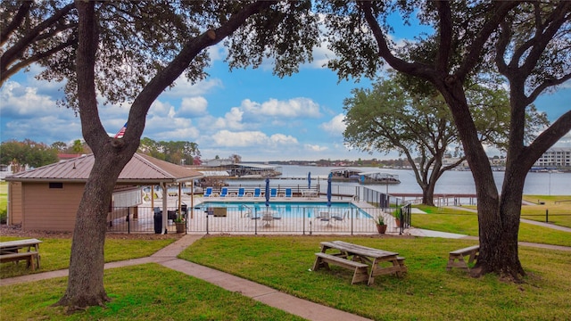 view of pool with a lawn and a water view