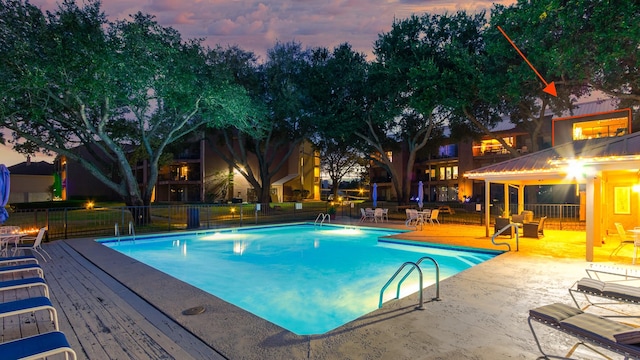 pool at dusk with a patio area and a wooden deck