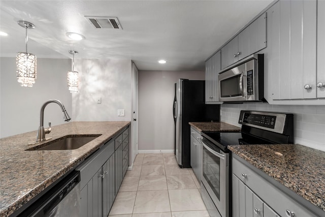 kitchen with sink, pendant lighting, gray cabinets, decorative backsplash, and appliances with stainless steel finishes