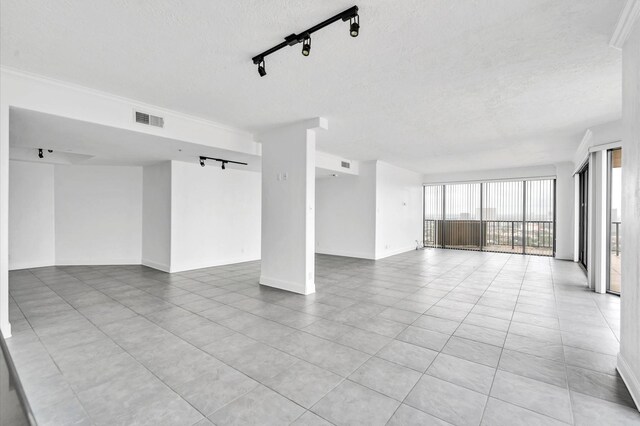 unfurnished room with a textured ceiling, light tile patterned floors, and track lighting