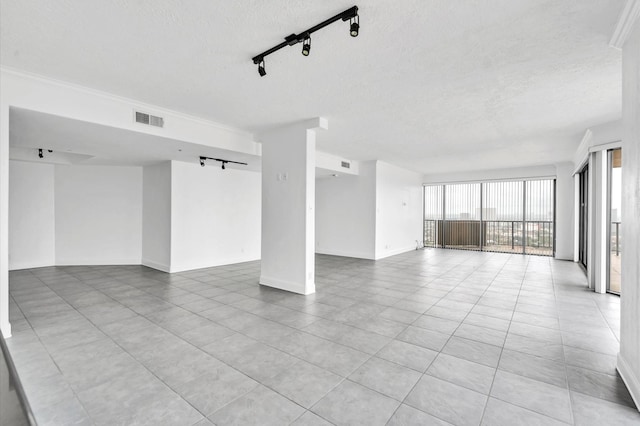 unfurnished room with baseboards, visible vents, rail lighting, and a textured ceiling