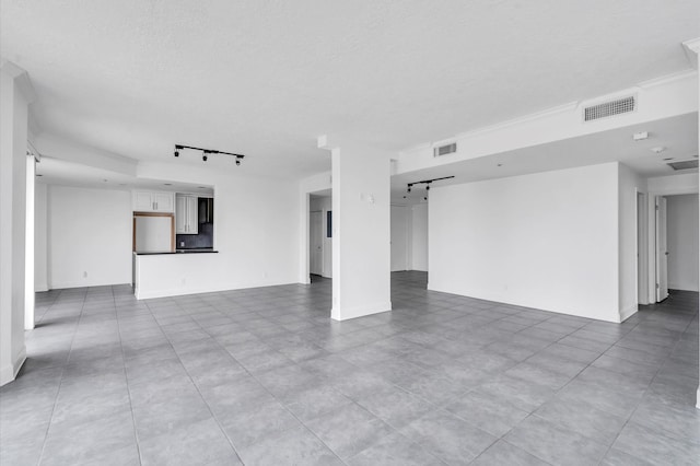 unfurnished living room featuring rail lighting, a textured ceiling, and visible vents