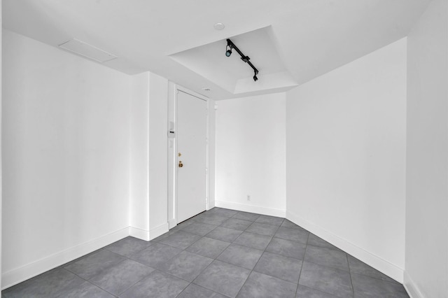 unfurnished room featuring baseboards, a tray ceiling, and track lighting
