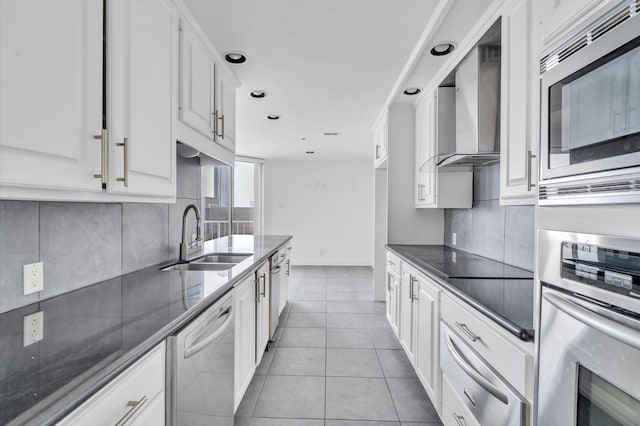 kitchen featuring a sink, wall chimney range hood, backsplash, and appliances with stainless steel finishes