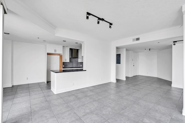 spare room featuring crown molding, rail lighting, and light tile patterned flooring