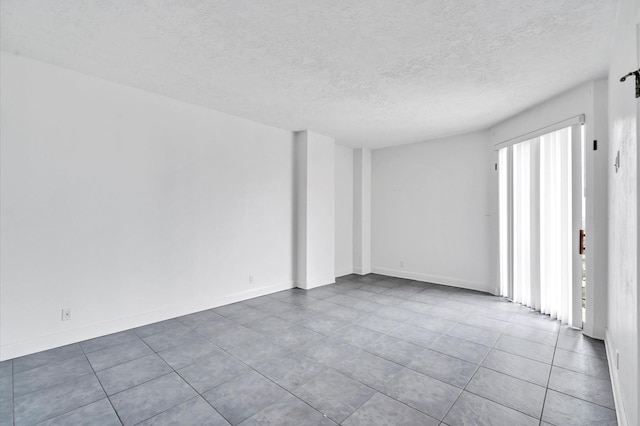 spare room featuring baseboards and a textured ceiling