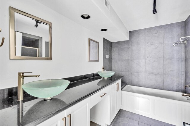 bathroom with tile patterned floors, tile walls,  shower combination, and vanity