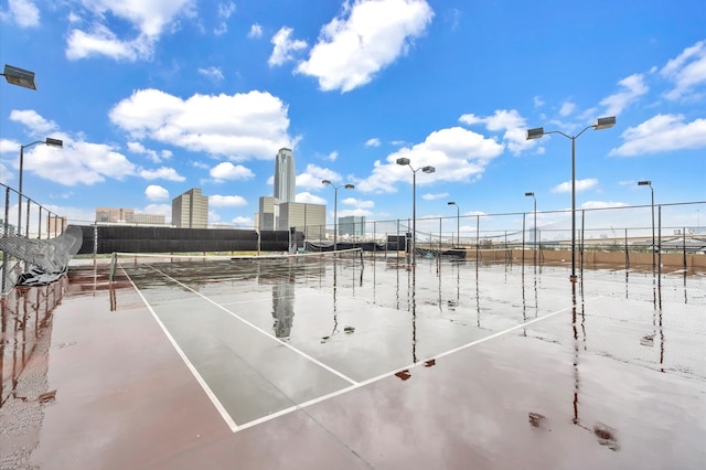 view of sport court with a view of city and fence