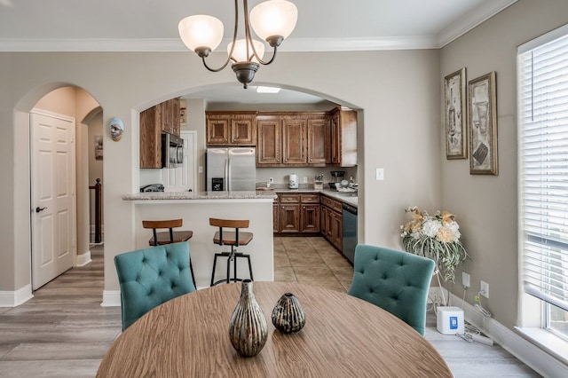 dining room featuring crown molding, plenty of natural light, an inviting chandelier, and light hardwood / wood-style floors