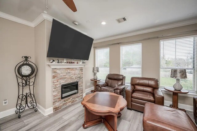 living room featuring a wealth of natural light, a stone fireplace, and light hardwood / wood-style floors