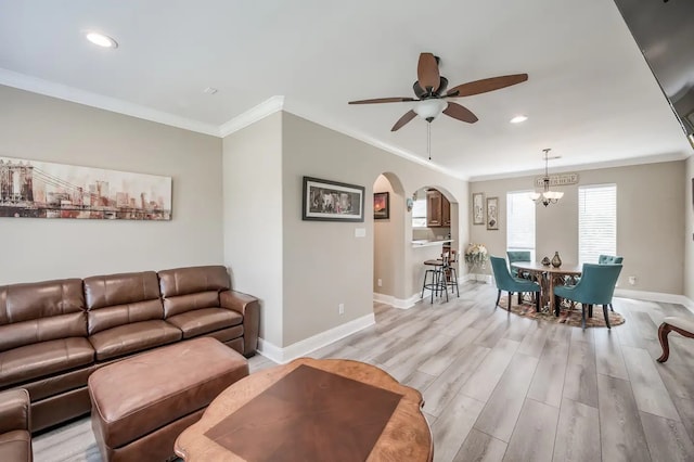 living room with ceiling fan with notable chandelier, ornamental molding, and light hardwood / wood-style flooring