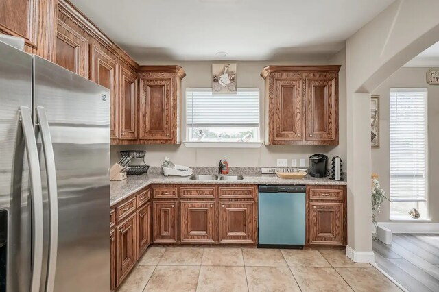 kitchen featuring light hardwood / wood-style flooring, stainless steel appliances, light stone counters, and sink