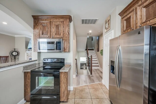 kitchen featuring light stone countertops, stainless steel appliances, ornamental molding, and light hardwood / wood-style flooring