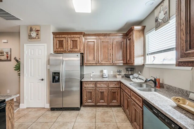 kitchen featuring light stone countertops, light tile patterned floors, stainless steel appliances, and sink