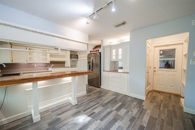 kitchen with dark hardwood / wood-style floors, stainless steel fridge, and white cabinets