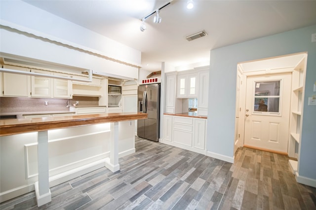 kitchen with wood counters, hardwood / wood-style floors, stainless steel fridge with ice dispenser, and white cabinets