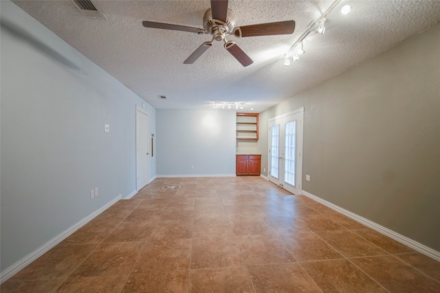 empty room featuring a textured ceiling, rail lighting, ceiling fan, and tile patterned flooring