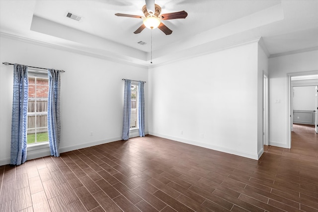 empty room featuring crown molding, a raised ceiling, ceiling fan, and dark hardwood / wood-style floors