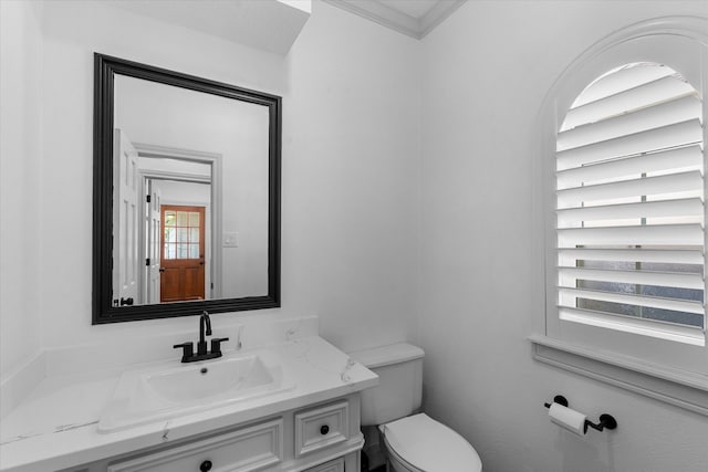 bathroom with ornamental molding, vanity, and toilet