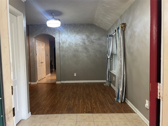 unfurnished room with light wood-type flooring and vaulted ceiling