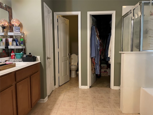 bathroom featuring tile patterned flooring, vanity, toilet, and a shower with shower door