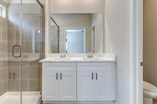 bathroom with double vanity, a stall shower, toilet, and a sink